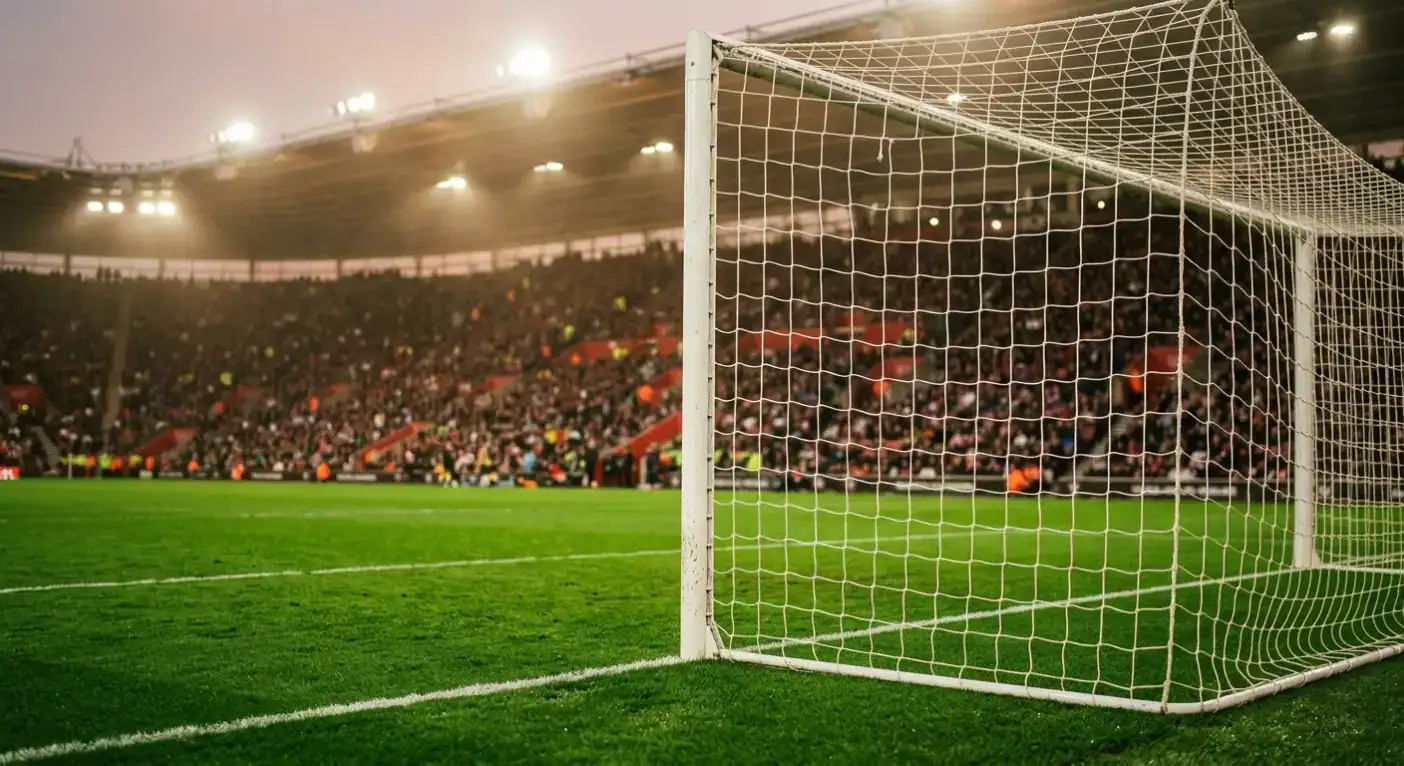 Futbola laukums lielā stadionā ar vārtu tīklu karstā vakara apgaismojumā